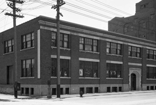 A two-story brick building with large windows and an arched entrance